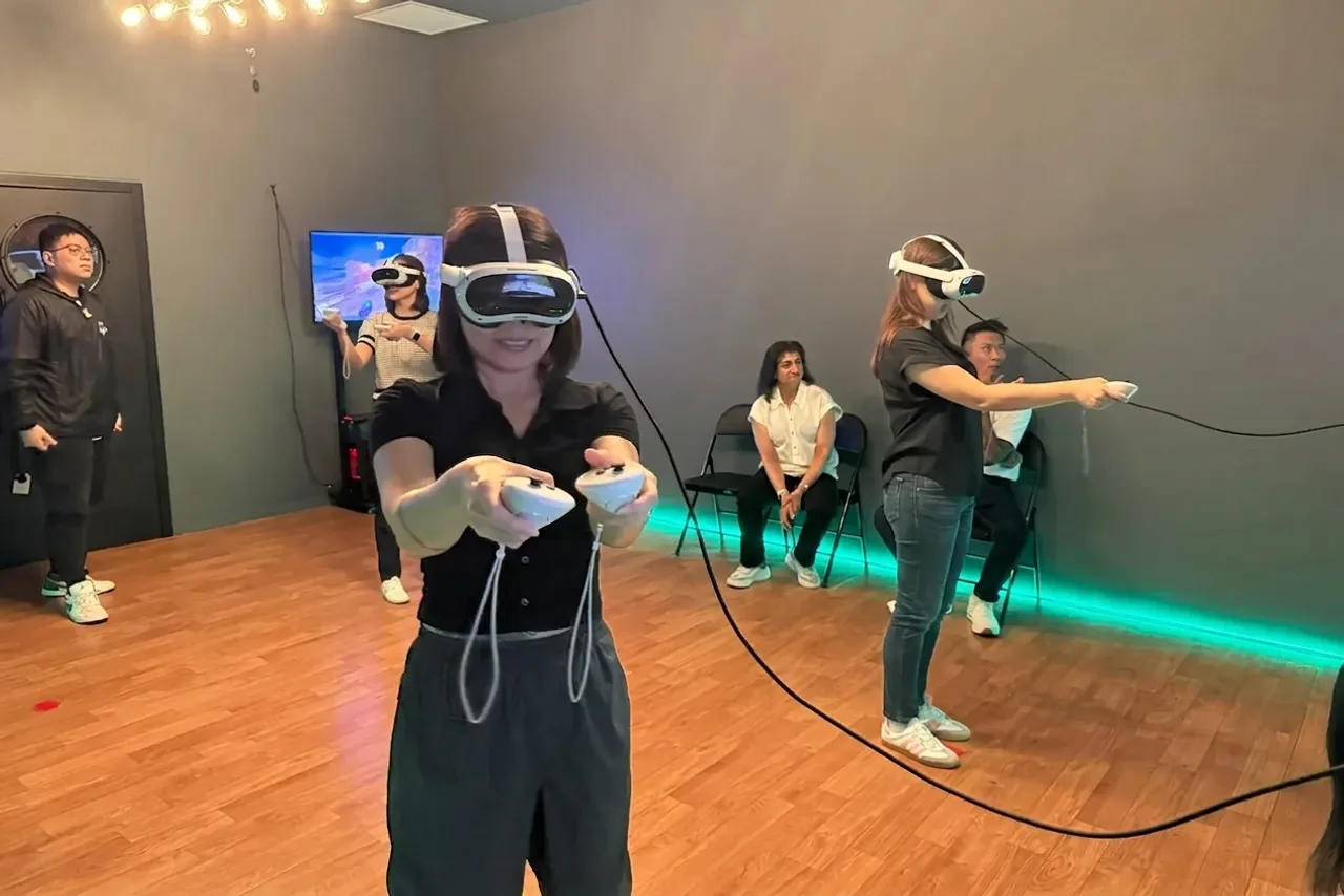 A player aiming both VR controllers mid-session in the VR arena at Lockdown Marina Square